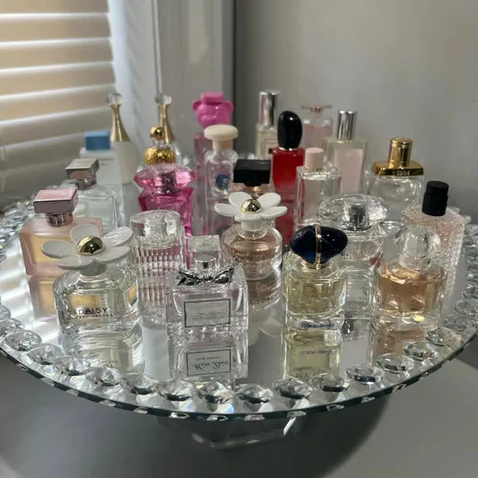 Empty decorative glass perfume bottles for home display, assorted shapes and sizes on mirrored tray